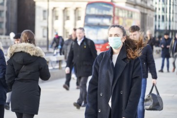 Young woman wearing face mask while walking in the streets of London