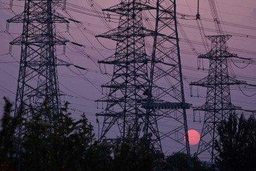 The sun sets behind electricity power pylons in Beijing on September 28, 2021. (Photo by LEO RAMIREZ / AFP)